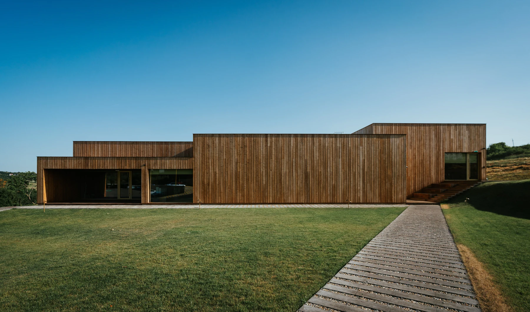 Modern timber-clad home with a walkway across the lawn